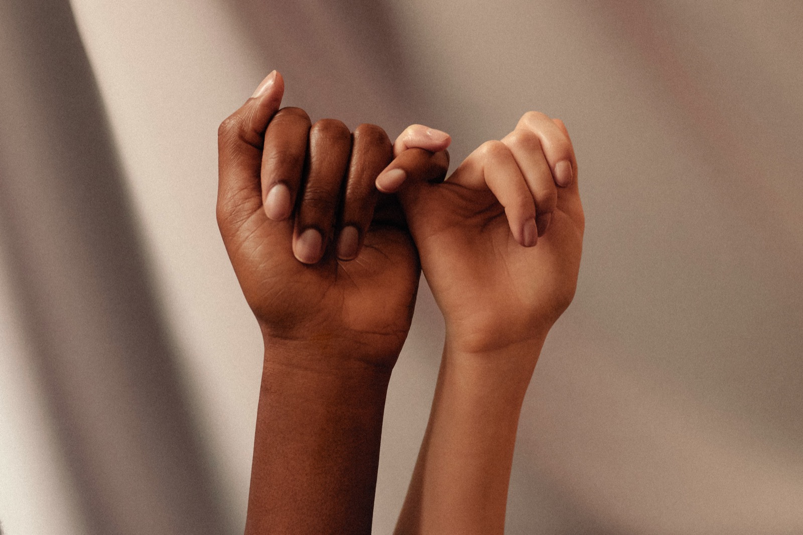 hands with interlocked pinky fingers and white manicures 📷 by Womanizer Toys on Unsplash